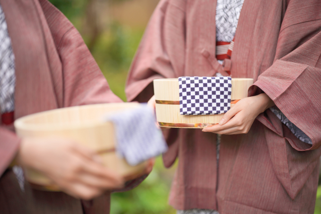 風呂桶を持った浴衣に羽織姿の女性の手元