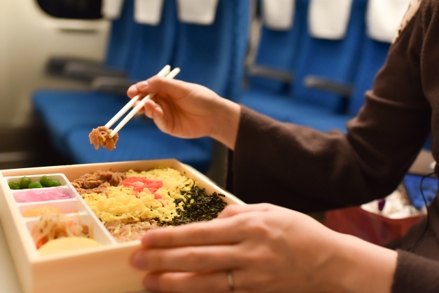 新幹線で駅弁を食べる人